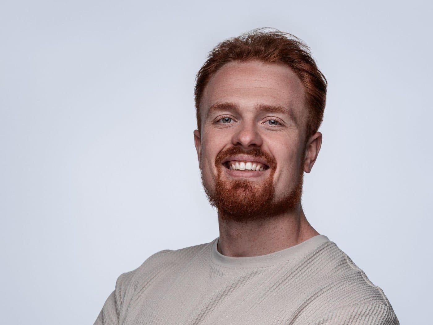 Darragh Gibbs in a cream T-shirt, arms crossed, smiling